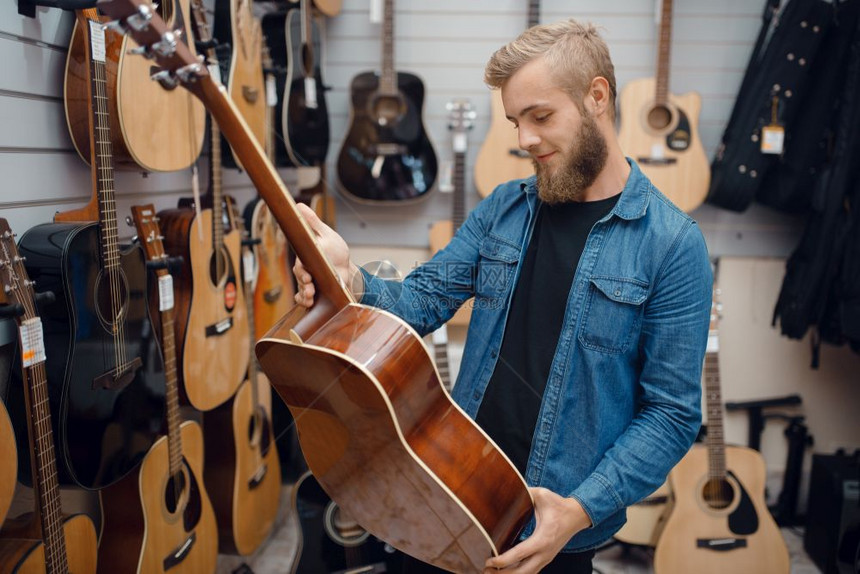 音乐店的吉他选手音乐器店的组合男音乐家购买设备