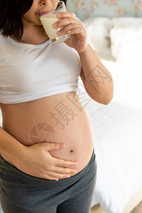 孕妇抚摸肚子喝着牛奶图片