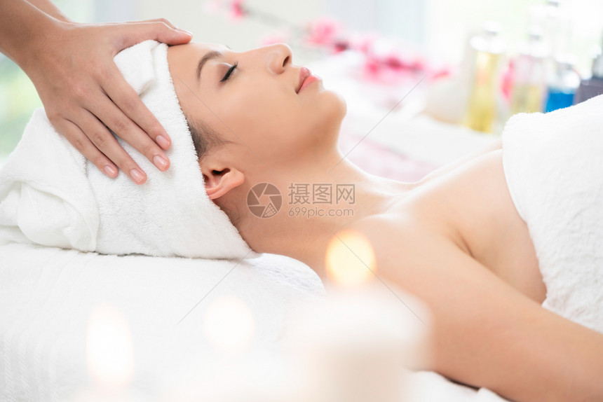 美女接受治疗师的面部和头按摩疗养图片