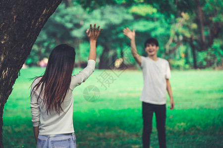 年轻人男和女在公园中挥手打招呼图片