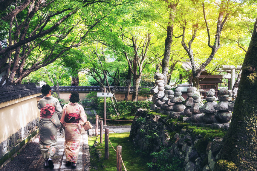 穿着传统的日本和服在古城京都的庙宇花园散步图片