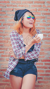 快乐的年轻时髦女人站在砖墙时尚高清图片素材