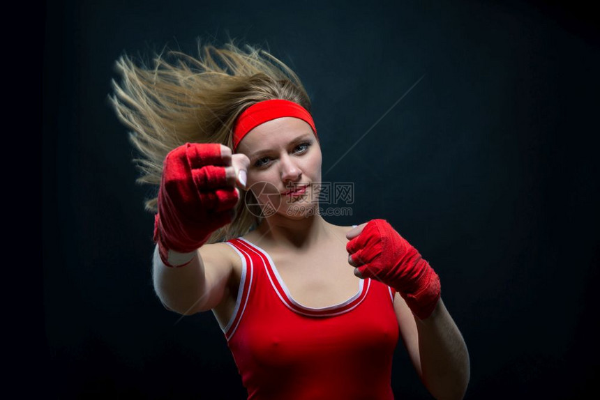 穿着红色拳击绷带和运动服训练的女拳击手图片