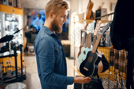 在音乐店中选择ukle吉他音乐器店中的各种组合男音乐家购买设备娱乐高清图片素材