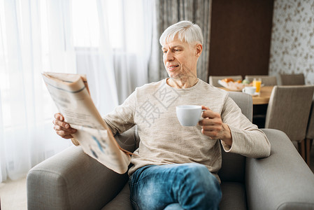 拿着咖啡杯的男人正在看报纸图片
