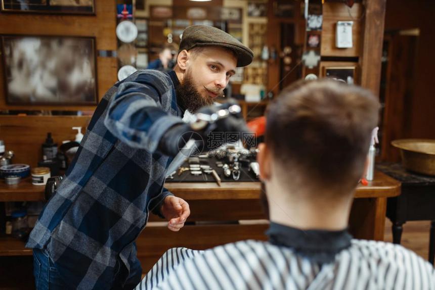 男理发师和顾客在倒型发廊理师向客户和进行图片