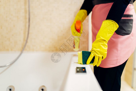 家庭主妇戴手套和围裙清洁浴缸图片