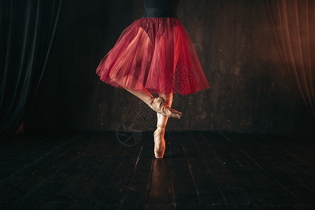 女芭蕾舞演员的腿是尖尖的红黑相间的芭蕾舞女演员在剧院的舞台上练习跳舞图片