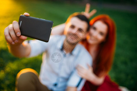 情侣坐在公园草地上自拍图片