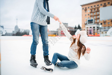 男子在滑冰场帮助女子站立图片
