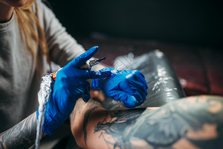 带纹身男女纹身用机器在肩膀上作纹身在沙龙做专业的纹身女用机器在男肩膀上做纹身背景