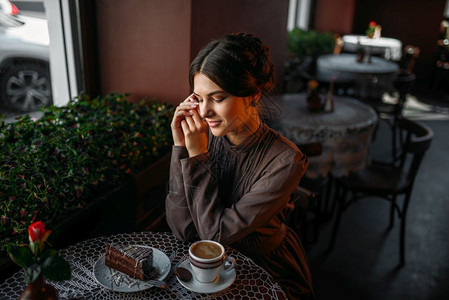 女孩在咖啡馆微笑着看向甜点和咖啡图片