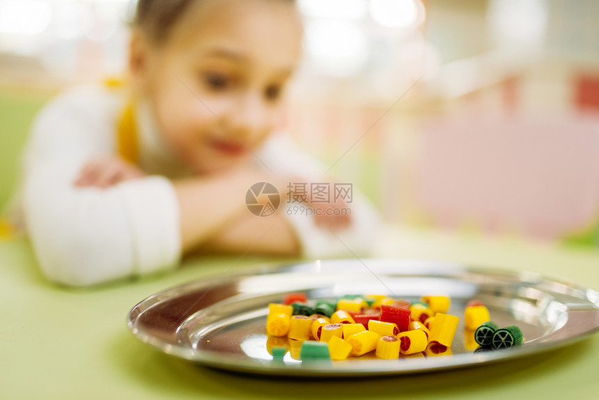 小女孩看着盘子里的糖果图片