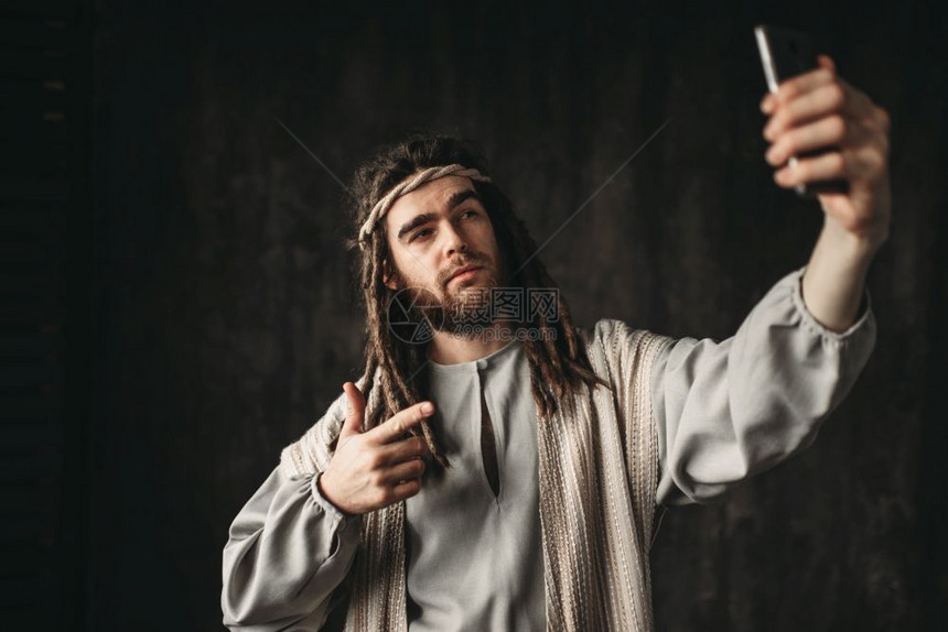 人类在基督的肖像中制作了手机上的自拍暗背景图片