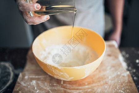男人面包师给面粉加食用油面团高清图片素材