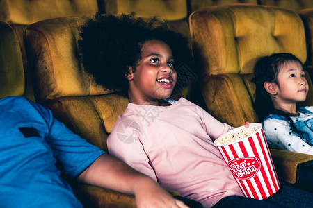 三个孩子玩得开心在电影院看电影微笑高清图片素材