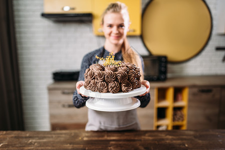烹饪女人展示巧克力蛋糕烹饪杰作厨房背景自制甜点图片