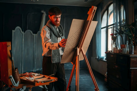 男画家手持调色盘和刷子在作画图片