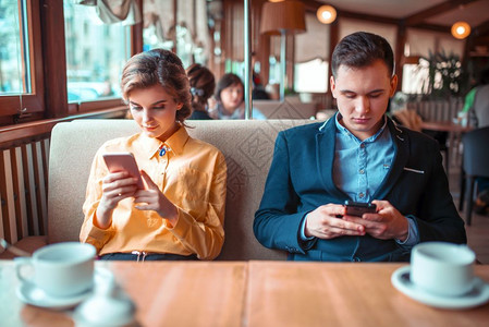情侣在餐厅约会时用手机令人愉快的高清图片素材