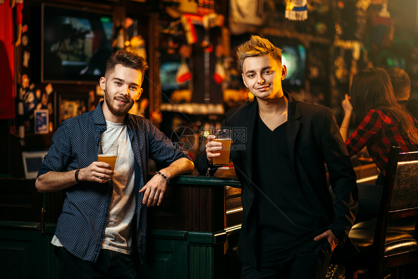 两人在酒吧柜台举起杯子喝啤酒图片