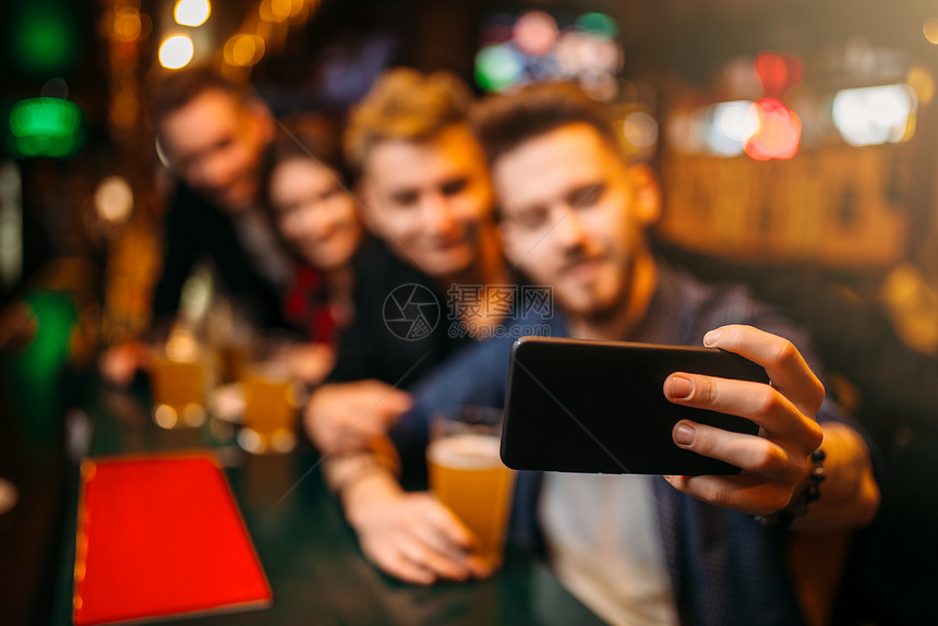 快乐的足球迷在酒吧的柜台用电话相机拍自图片