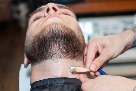 双刀头剃须刀理发师与剃须刀一起在沙龙工作背景