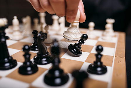 回子形男象棋手握着白形特端棋手移动吃掉黑当子有选择的焦点智战在棋盘上的概念背景
