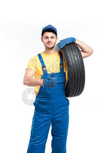 穿蓝色制服的轮胎工人手持汽车轮胎图片