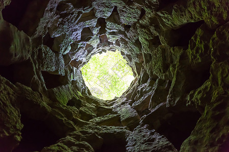 从圆窄洞穴的底部视图窄洞的尽头有光线背景图片