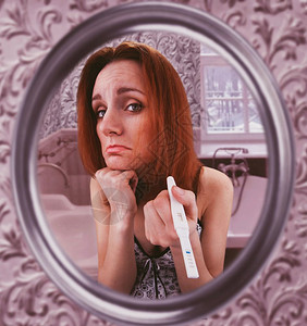 悲伤的女子在镜里看着她的怀孕测试显示怀孕测试的妇女图片