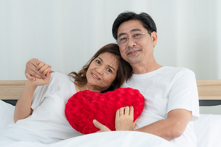 夫妻在床上抱着心形抱枕图片