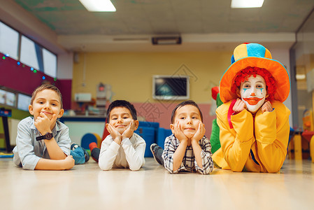 孩子们与小丑一起快乐的玩耍闲小丑和孩子躺在地上图片