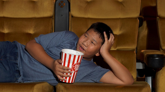 男孩躺在扶手椅上享受着看电影电影院高清图片素材