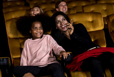 女人和女儿一起在电影院看电影微笑高清图片素材