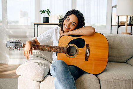 坐在沙发上拿吉他的女人乐趣高清图片素材
