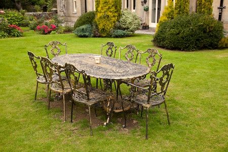 旧式金色铁铸桌和正式草坪上的八张椅子图片