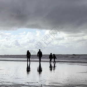 幸福的家庭在海滩上漫步图片
