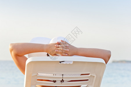 妇女在沙滩度假时坐休息椅上图片
