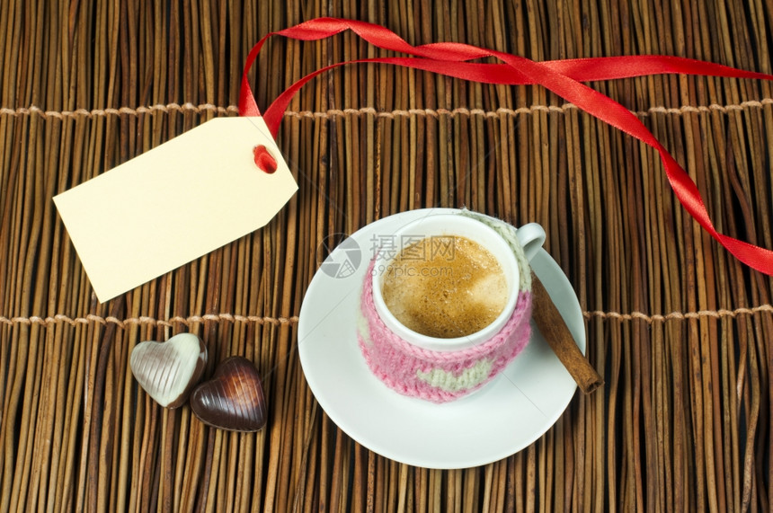咖啡杯有编织的心脏符号和标签在木制底座上图片