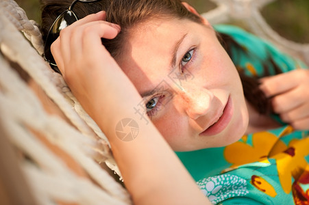 女人躺在吊床上看着摄像机头发高清图片素材