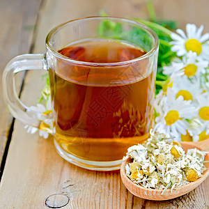 一杯茶木勺子干甘菊花木板背景上一束鲜香菊花图片