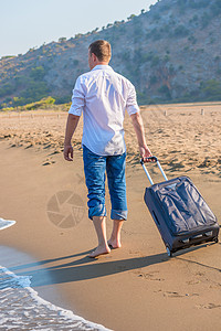 男人带着手提箱走在沙滩上图片