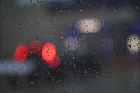 脾脏降雨时通过湿挡风玻璃看见的红色交通灯背景