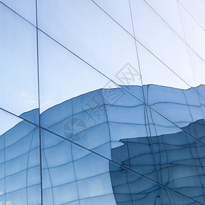 具有蓝色天空和玻璃墙反射力的现代玻璃建筑图片
