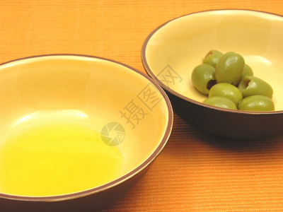 两碗含橄榄油的陶瓷和橙色底橄榄图片