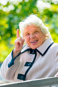 快乐的祖母坐在公园长凳上图片