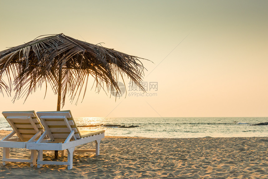 沙滩上被吊在雨伞下的空椅子图片