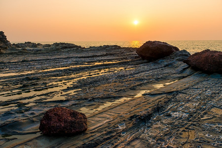 美丽的日落在海面和岩石上图片