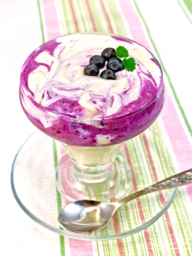 甜牛奶蓝莓玉米片卷饼勺子放在一桌布背景的玻璃餐具中图片
