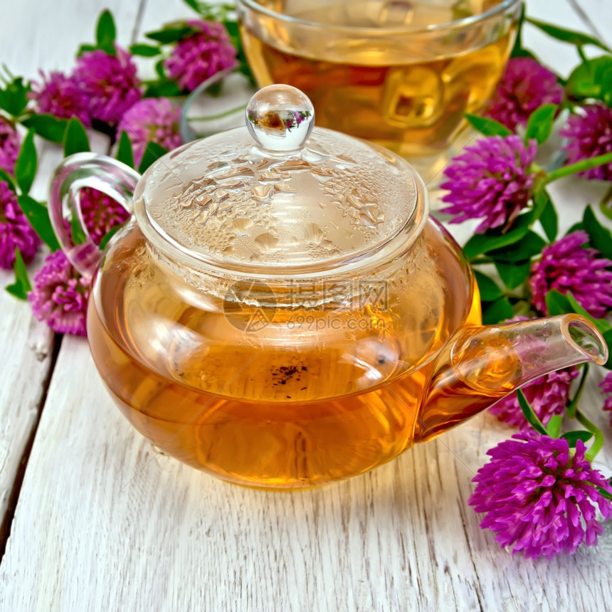 在玻璃茶壶和杯子中用花朵装有青柳的草药茶在底浅木板上用杯子图片